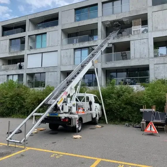 Möbellift von Activ Umzüge, ausgefahren an der Fassade eines Wohngebäudes