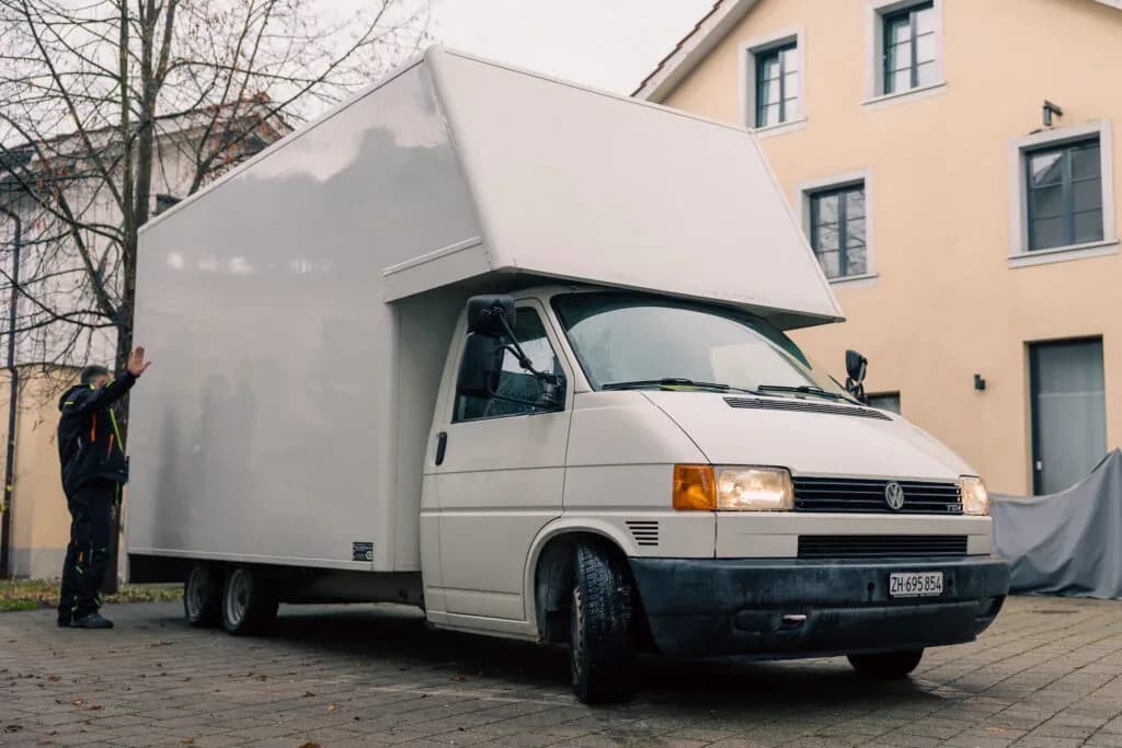 Umzugsfahrzeug von Activ Umzüge vor einem Wohnhaus, ein Mitarbeiter belädt den Wagen